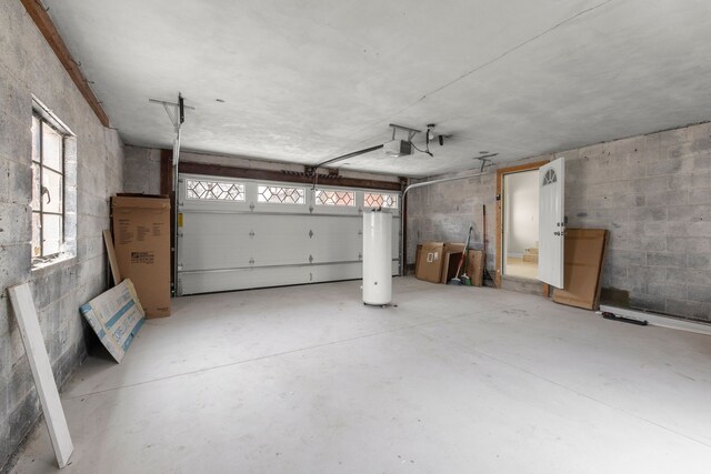 garage with concrete block wall, water heater, and a garage door opener