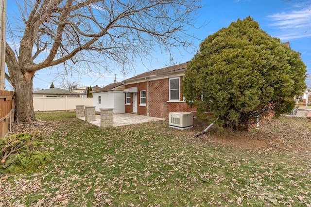 back of property featuring a fenced backyard, a patio, a lawn, and brick siding