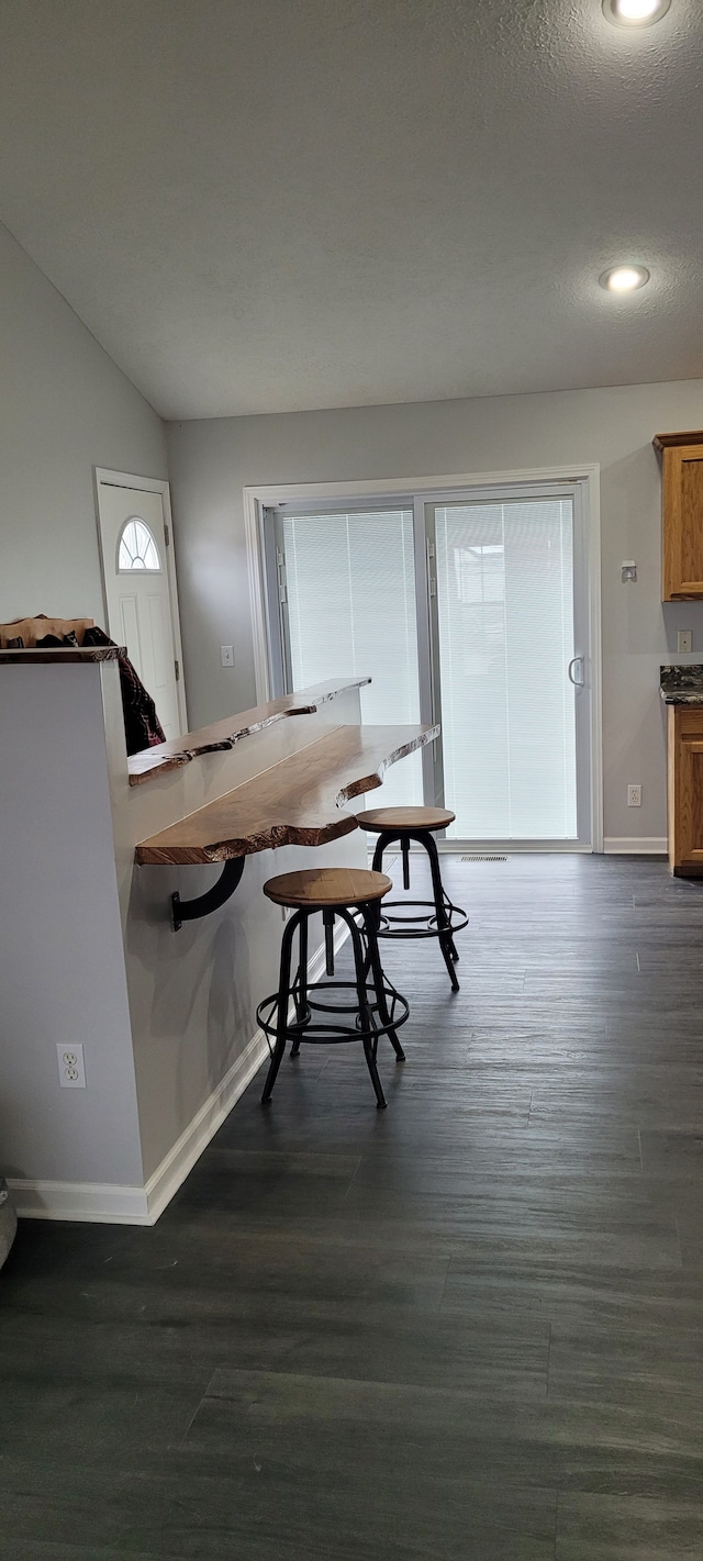 dining area featuring a textured ceiling, dark hardwood / wood-style flooring, and vaulted ceiling