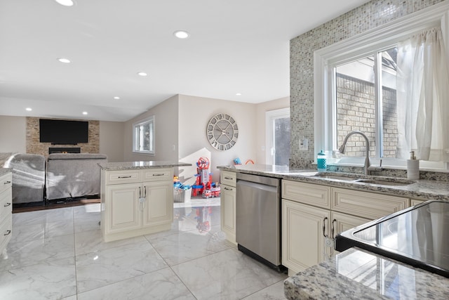 kitchen with dishwasher, cream cabinetry, range with electric cooktop, light stone countertops, and sink