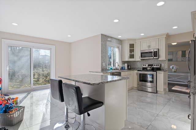 kitchen with light stone counters, appliances with stainless steel finishes, and a wealth of natural light