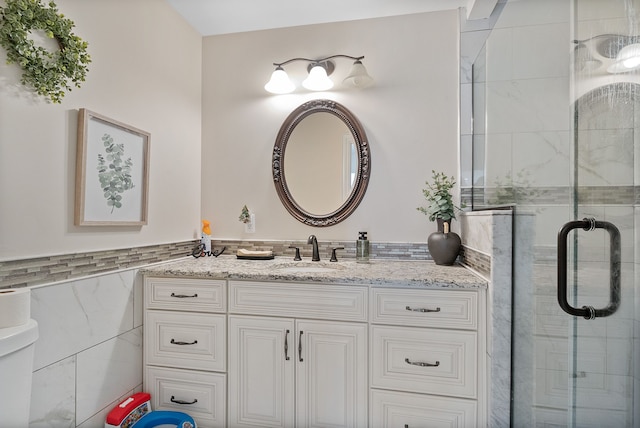 bathroom with tile walls, an enclosed shower, and vanity