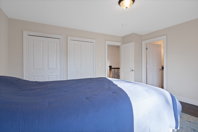 bedroom featuring two closets and dark hardwood / wood-style floors