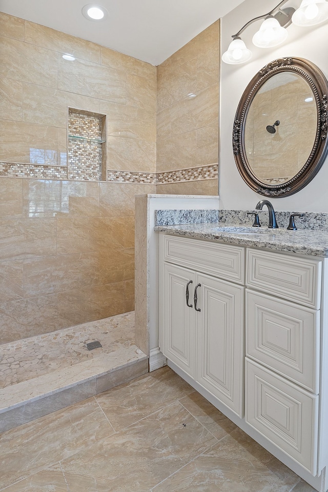 bathroom with a tile shower and vanity