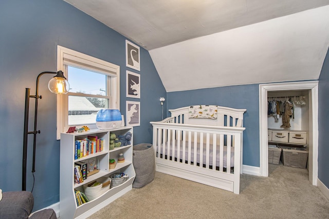 bedroom with a crib, carpet flooring, and vaulted ceiling