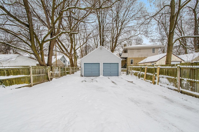 snowy yard featuring a garage and an outdoor structure