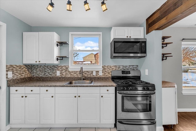 kitchen with white cabinetry, appliances with stainless steel finishes, sink, and backsplash