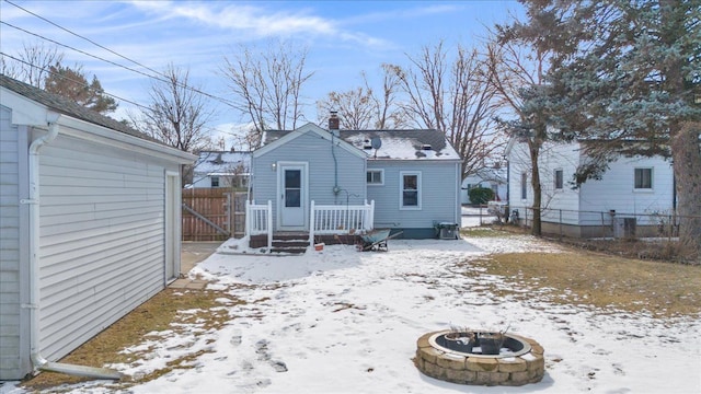 snow covered back of property with an outdoor fire pit