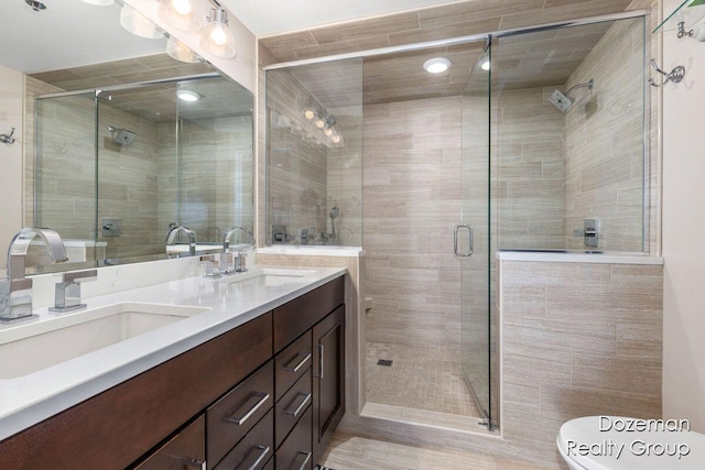 bathroom featuring toilet, a shower with shower door, and vanity