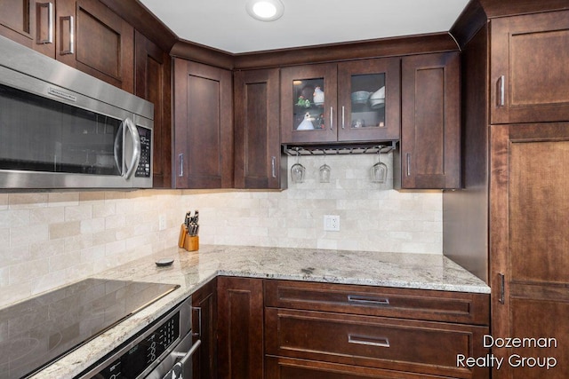 kitchen featuring wall oven, decorative backsplash, dark brown cabinets, and light stone counters