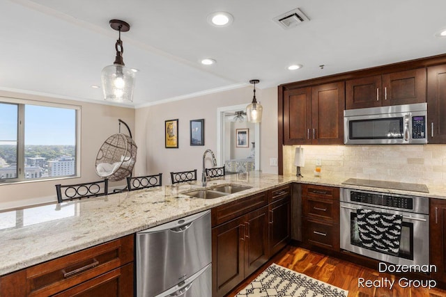 kitchen with stainless steel appliances, sink, pendant lighting, and kitchen peninsula