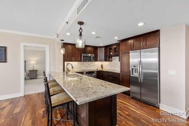 kitchen featuring stainless steel appliances, kitchen peninsula, pendant lighting, sink, and dark brown cabinets