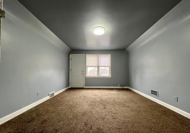 carpeted spare room with vaulted ceiling