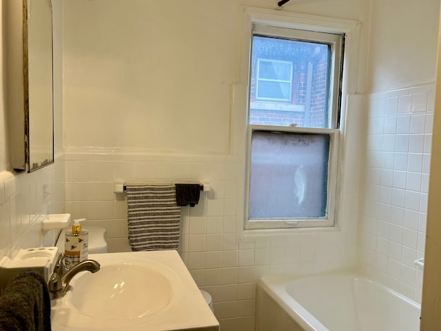 bathroom with tile walls, a tub, and sink