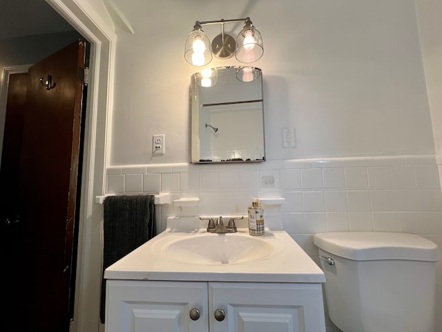 bathroom with toilet, tile walls, and vanity