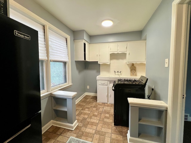 kitchen with sink, black appliances, tasteful backsplash, and white cabinetry