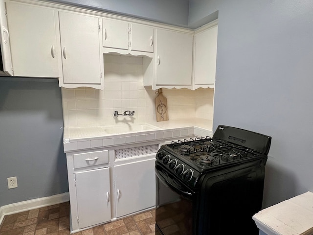 kitchen featuring white cabinets, tasteful backsplash, gas stove, and sink