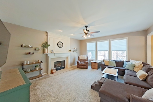 carpeted living room featuring a large fireplace and ceiling fan