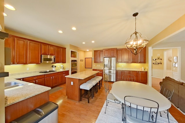 kitchen featuring a breakfast bar, a kitchen island, pendant lighting, stainless steel appliances, and light hardwood / wood-style floors