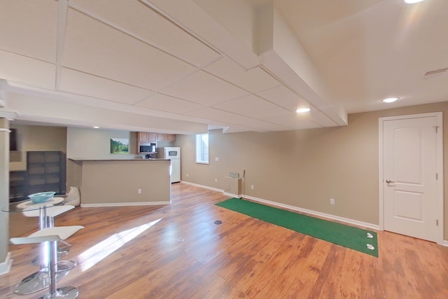 basement with white refrigerator and light hardwood / wood-style flooring