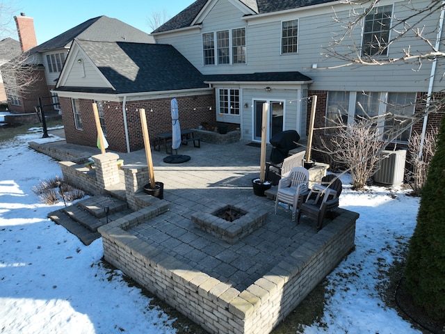 snow covered house with central AC, an outdoor fire pit, and a patio