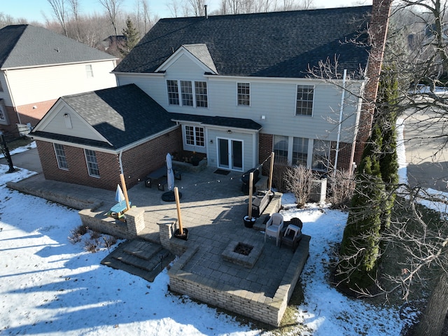 snow covered back of property featuring a patio and an outdoor fire pit