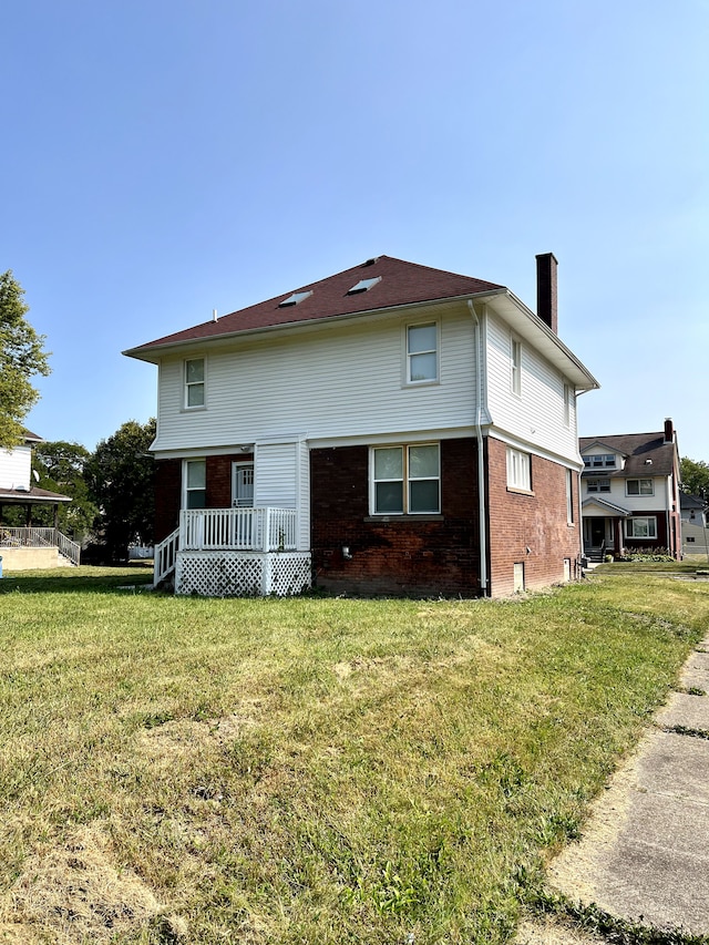 back of house featuring brick siding, a lawn, and a chimney