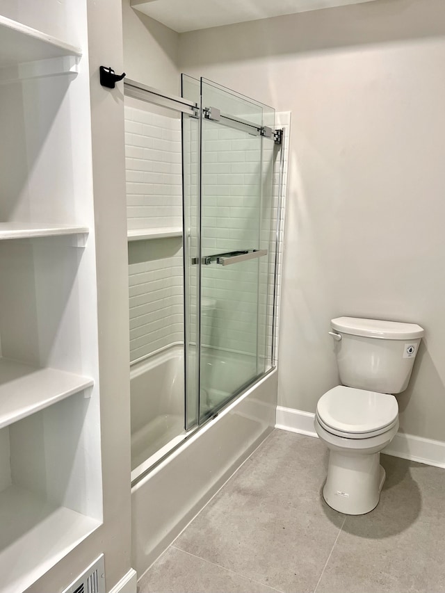 bathroom with tile patterned flooring, bath / shower combo with glass door, and toilet