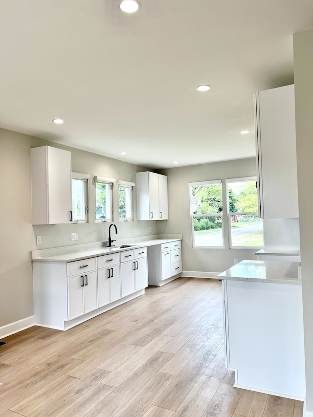 kitchen featuring sink, white cabinetry, and light wood-type flooring