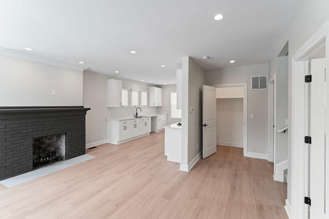 unfurnished living room with baseboards, visible vents, light wood finished floors, recessed lighting, and a sink