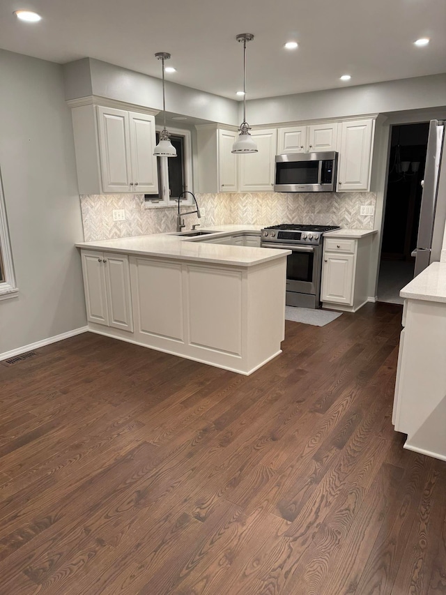 kitchen featuring appliances with stainless steel finishes, sink, kitchen peninsula, and decorative light fixtures