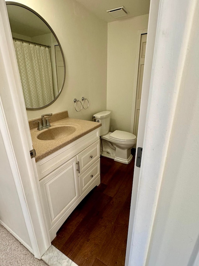 bathroom featuring toilet, vanity, and hardwood / wood-style floors