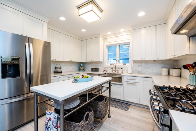 kitchen with stainless steel appliances, white cabinetry, exhaust hood, and a kitchen breakfast bar