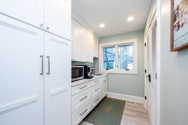 kitchen featuring white cabinets, light wood-type flooring, and sink