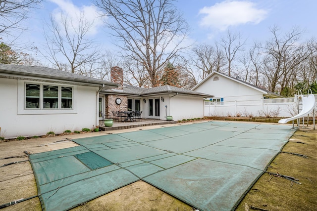 back of house with a covered pool and a patio