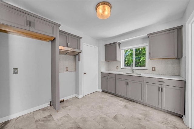 kitchen with gray cabinets, decorative backsplash, and sink