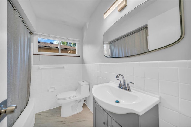 full bathroom featuring tile walls, shower / bath combo with shower curtain, vanity, and toilet