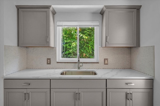 kitchen featuring sink, light stone counters, and gray cabinets