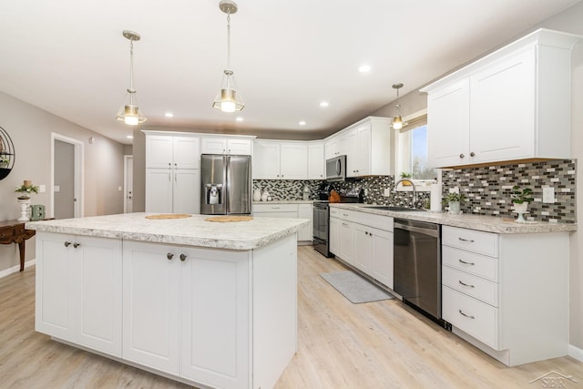 kitchen featuring appliances with stainless steel finishes, a center island, pendant lighting, white cabinets, and sink