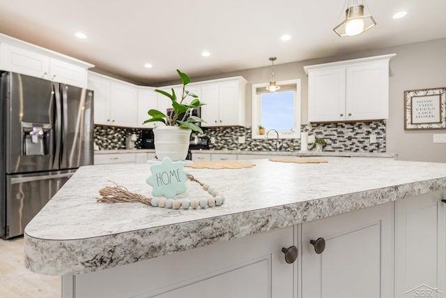 kitchen with light hardwood / wood-style flooring, pendant lighting, stainless steel refrigerator with ice dispenser, white cabinets, and sink