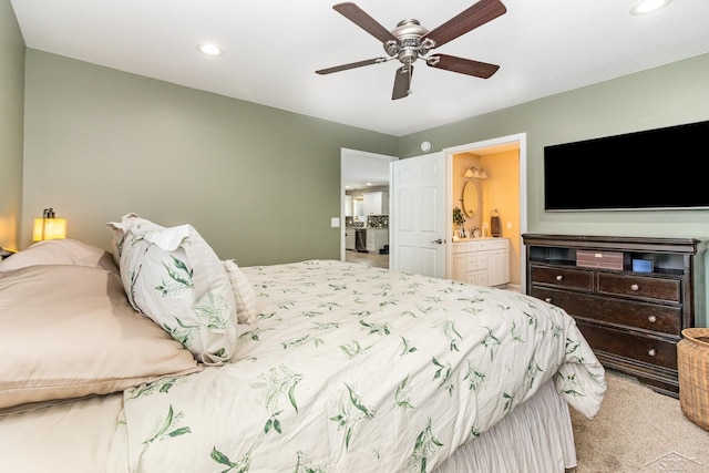 bedroom with connected bathroom, light carpet, and ceiling fan