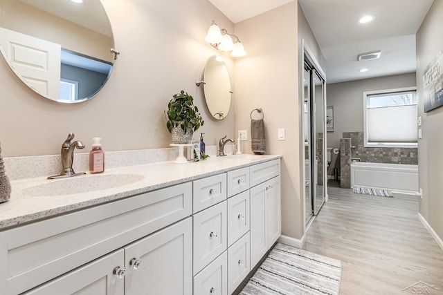 bathroom featuring a washtub, wood-type flooring, and vanity