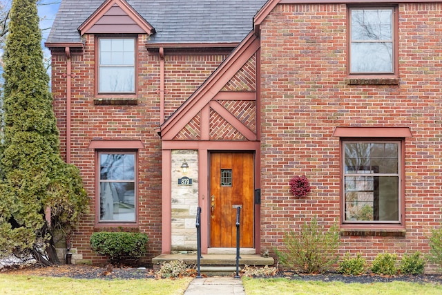 view of front facade with a shingled roof and brick siding