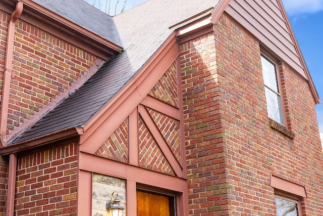 view of side of home featuring a shingled roof and brick siding