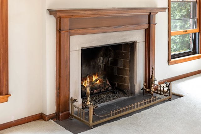 interior details with a warm lit fireplace and baseboards