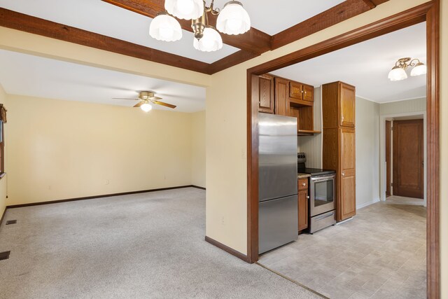 kitchen featuring light colored carpet, appliances with stainless steel finishes, brown cabinetry, beamed ceiling, and baseboards