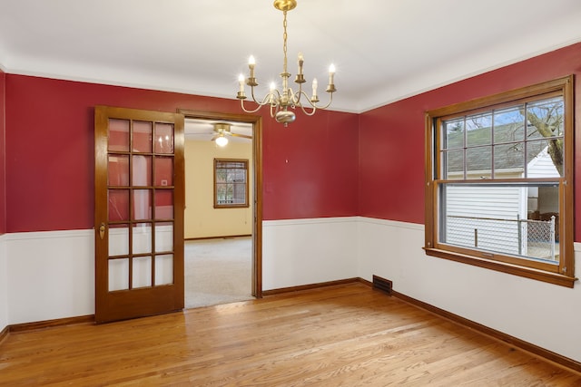 unfurnished dining area featuring a chandelier, light wood-style flooring, and baseboards