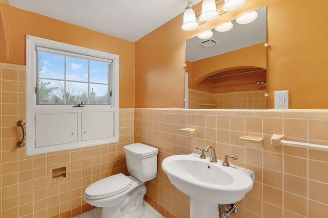 full bathroom featuring a wainscoted wall, tile walls, visible vents, toilet, and a sink