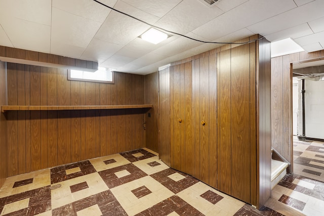 below grade area with stairs, wood walls, and tile patterned floors