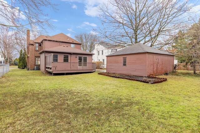 back of property with fence, a deck, and a yard